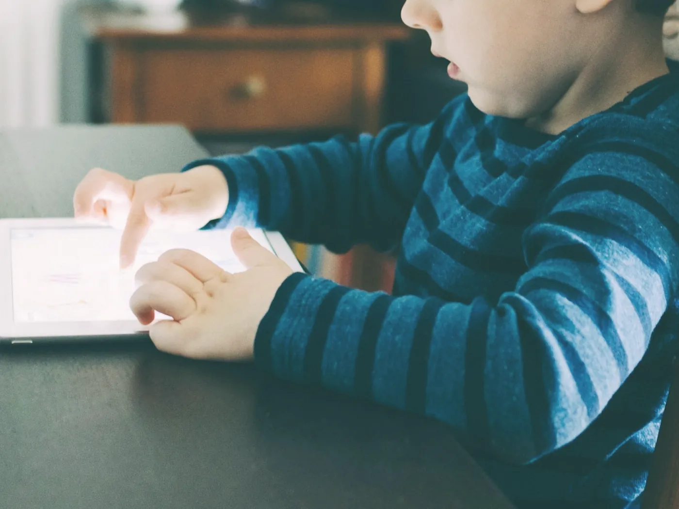 Çizgili kazaklı bir çocuğun ellerinde tuttuğu tablet, yakın çekim